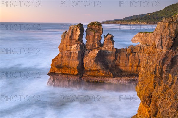 Rock formations on the coast of Paparoa National Park in red evening sun, Punakaiki