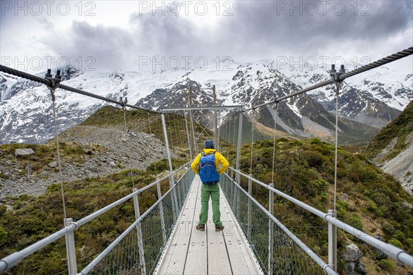 Hiker crosses suspension bridge over Hooker River, Hooker Valley