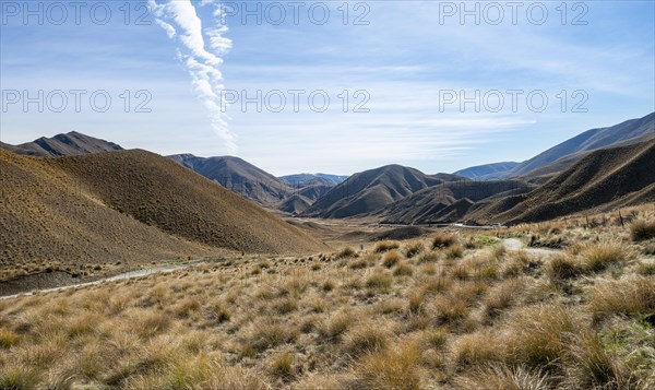 Barren mountain landscape with tufts of grass, Lindis Pass