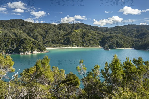 Green sea with yellow sandy beach, tropical hills in the back