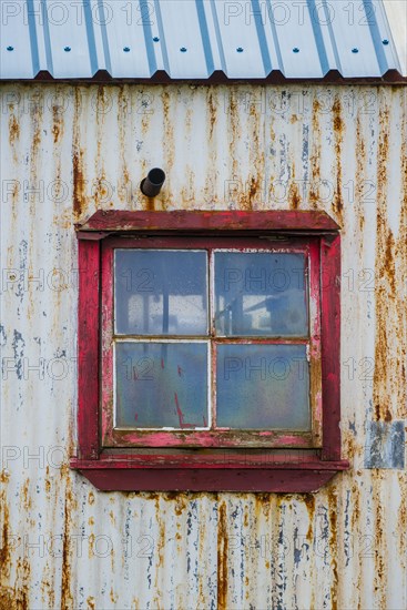 Rusty, weathered corrugated iron facade with window