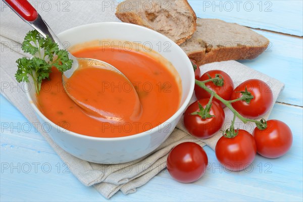Tomato soup with spoon in bowl, tomatoes