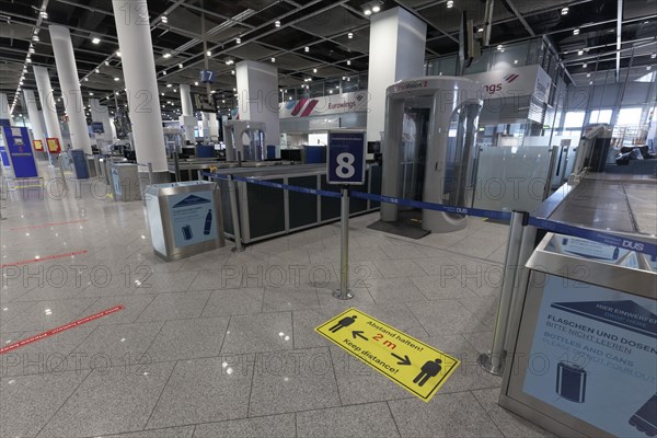 Sign with distance rule in front of the deserted baggage check, flight ban due to corona pandemic