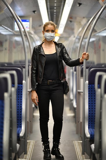 Woman with face mask, standing in suburban train