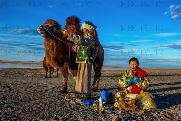 Two Mongolians in traditional dress with trampling animals at prayer