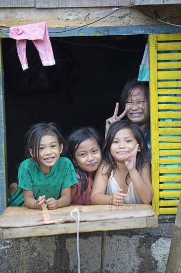 Happy children looking out of the window of their house