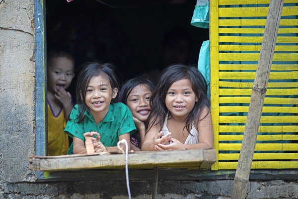 Happy children looking out of the window of their house