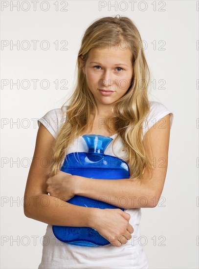 Sick girl with hot water bottle has stomach ache