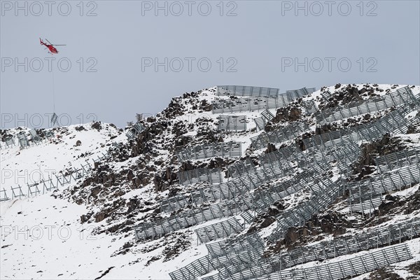 Helicopter transports fences for avalanche protection