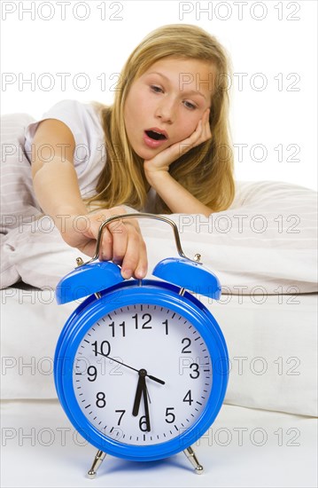 Girl in bed yawns when the alarm clock rings