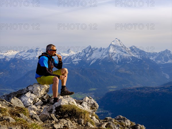 Mountaineer with a snack at the summit Rauher Kopf