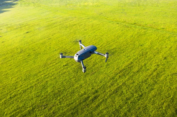 Flying drone DJI Mavic 2 Pro from above over meadow