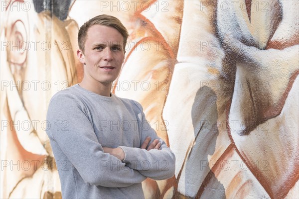 Young man in front of graffiti wall