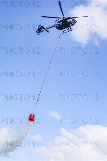 Police helicopter Airbus H 145 during exercise with fire water tank BAMBI BUCKET