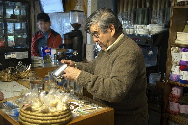 Shopkeeper brewing and serving cappuccino