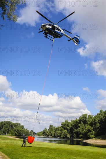 Police helicopter Airbus H 145 during exercise with fire water tank BAMBI BUCKET