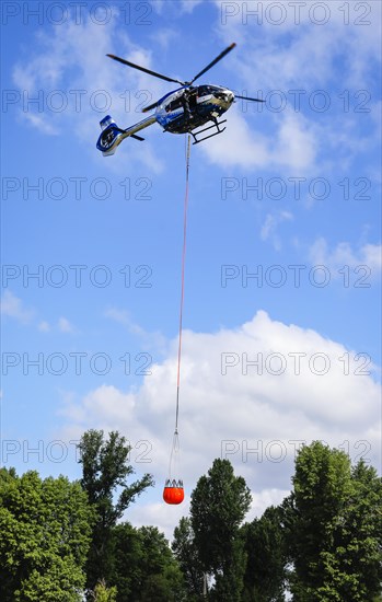 Police helicopter Airbus H 145 during exercise with fire water tank BAMBI BUCKET