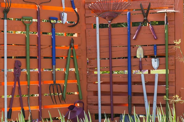 Various garden tools hanging on wooden wall Shovels