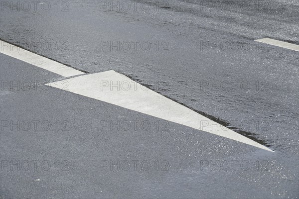Directional arrow on rain wet road