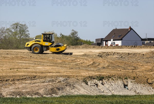 A road roller compacts the dam above the elevated sewer in the construction site