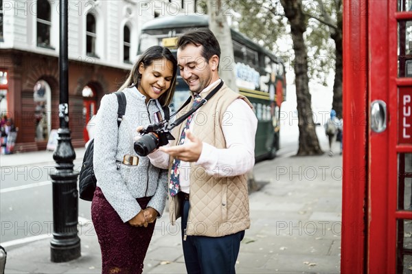 Happy traveling couple looking at photos on their camera