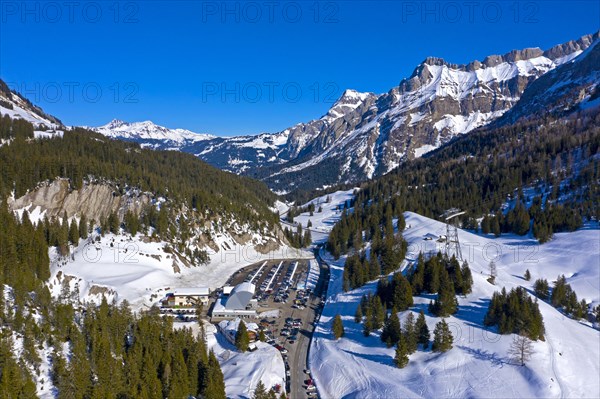 Car park and valley station of the Glacier 3000 aerial cableway to the Glacier des Diablerets ski area on the Col du Pillon mountain pass in winter