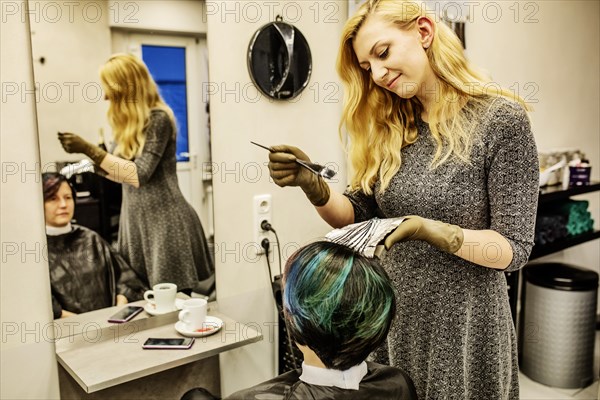 Hairdresser in a hairdressing salon dying strands of hair with aluminium foil