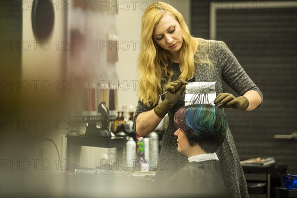 Hairdresser in a hairdressing salon dying strands of hair with aluminium foil