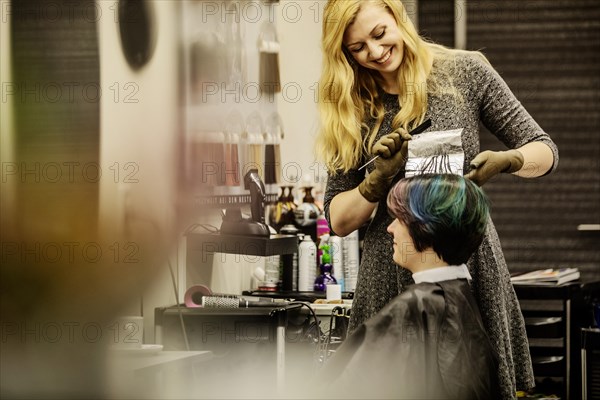 Hairdresser in a hairdressing salon dying strands of hair with aluminium foil