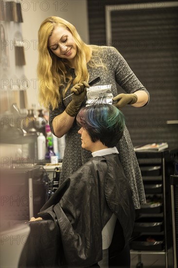 Hairdresser in a hairdressing salon dying strands of hair with aluminium foil