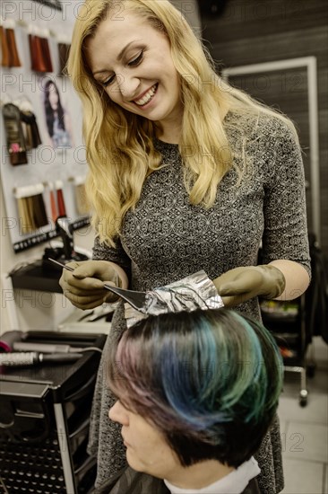 Hairdresser in a hairdressing salon dying strands of hair with aluminium foil