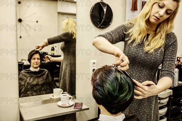 Hairdresser cuts the hair of a customer in front of a mirror in a hairdressing salon