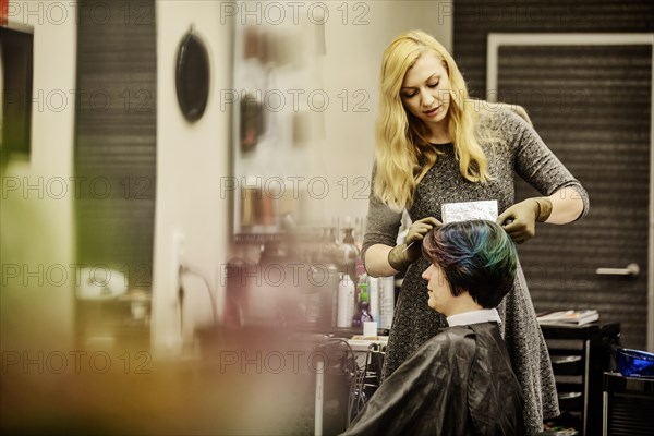 Hairdresser in a hairdressing salon dying strands of hair with aluminium foil