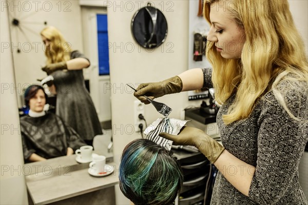 Hairdresser in a hairdressing salon dying strands of hair with aluminium foil