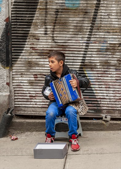 A boy playing the accordion on the road