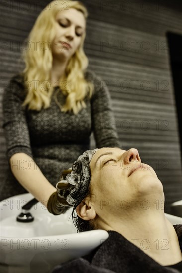 Hairdresser in a hairdressing salon washes a customer's hair over a basin