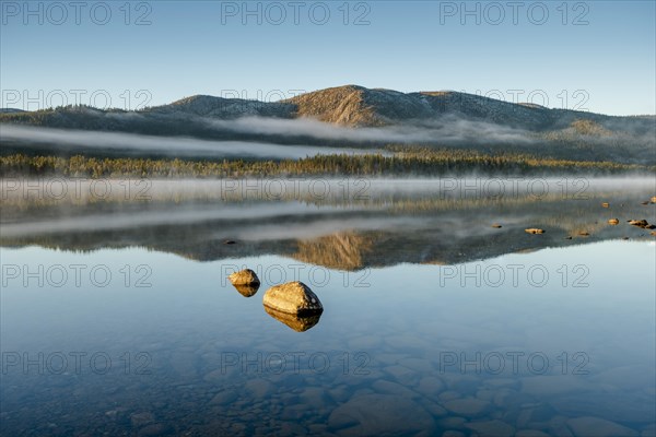 Autumnal fog atmosphere on the lake shore in the evening light