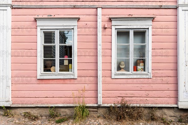 Pink painted wooden house facade with two windows