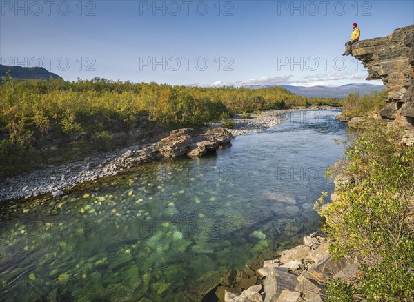 Man sitting on stone cliff over the river Abiskojakka