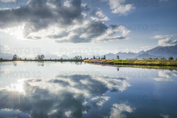 Mountain biker with e-bike on the lakeside in front of a mountain scenery