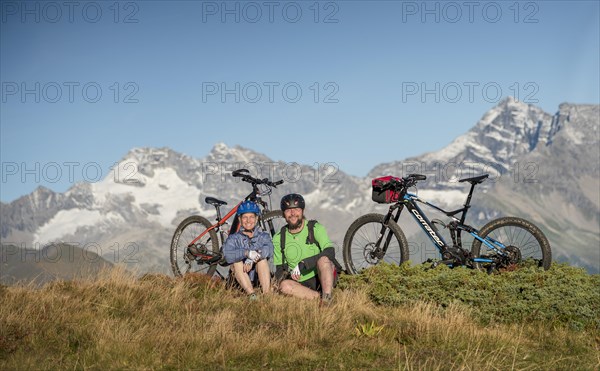 Mountain biker couple sitting next to eBikes in the autumnal mountain scenery of the Stubaier Alps