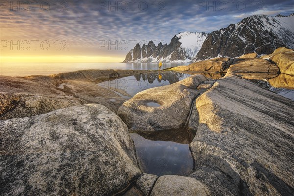 Person with yellow jacket standing on the rocky beach of Tungeneset