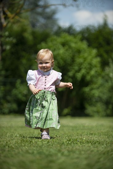 Girl in Dirndl runs across a meadow