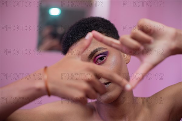 Young man with make-up makes gesture with his hands