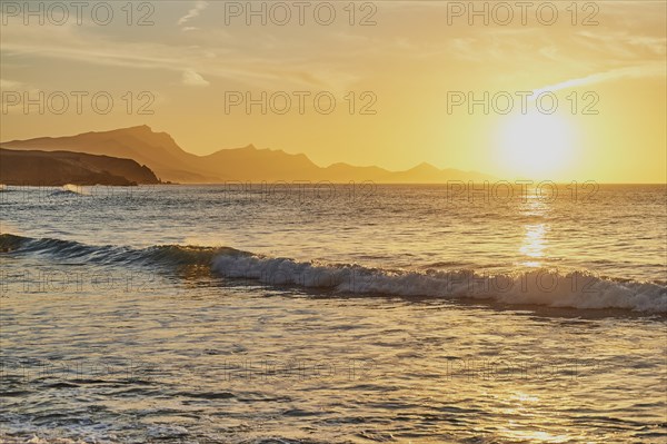 Beach Playa de la Pared with rocky coast at sunset