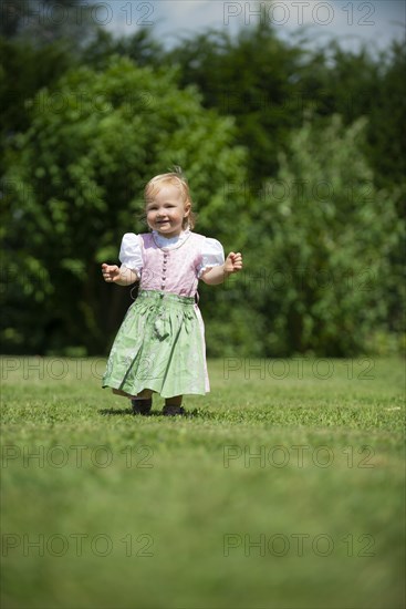 Girl in Dirndl runs across a meadow