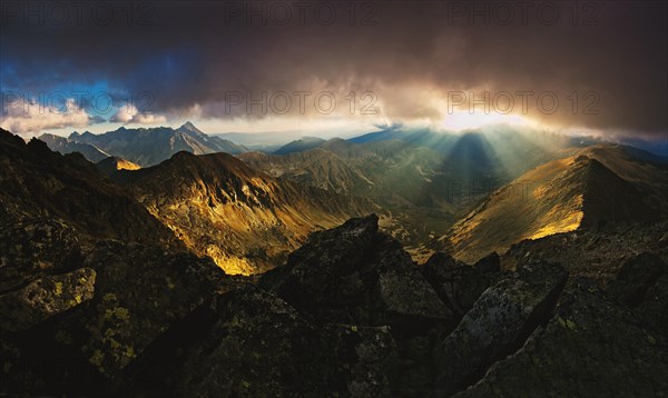 The rays of the setting sun that break through the peaks and clouds
