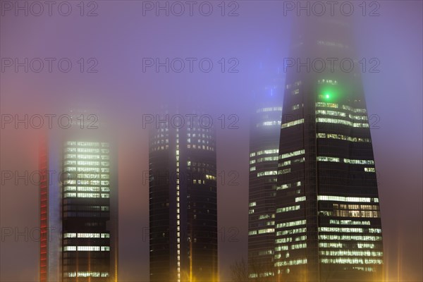 Cuatro Torres Business Area Office building illuminated in evening fog