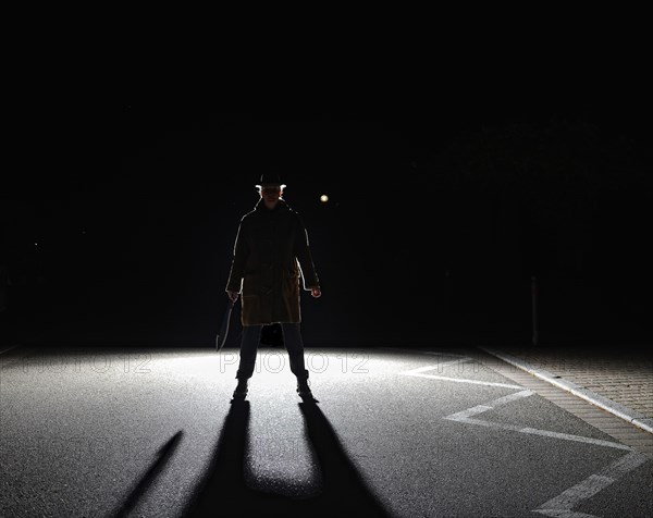 Woman with big knife in backlight with black shadow