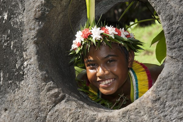 Native boy from Yap looks through stone money hole